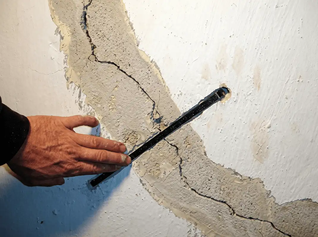 A wall with a large crack is being inspected by a professional in San Diego, CA