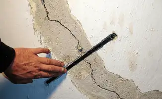 A wall with a large crack is being inspected by a professional in San Diego, CA